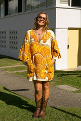 60s inspired mini smock dress with bell sleeves, patch pockets and a v-neckline. Features a bold, large-scale mustard and brown retro geo print. Made in 100% cotton
