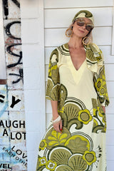 70s inspired maxi kaftan-style dress with bell sleeves , retro patch pockets and a v-neckline. Features a bold, large-scale retro geo print. in rich green tones. Made in 100% cotton