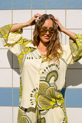 70s style button-up top with a stament retro collar and bell sleeves, featuring a bold large-scale floral print in rich green and cream tones, crafted from 100% rayon for a soft, flowing fit.