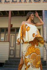 Bohemian style one shoulder maxi dress featuring a long, flowy frill that covers one arm and drapes elegantly down to the hips. This dress has side splits and showcases a large-scale bold, retro inspired print in rich mustard, brown and cream tones. Made in 100% rayon.