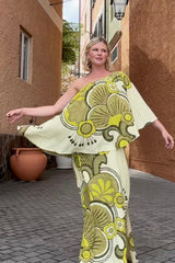 Bohemian style one shoulder maxi dress featuring a long, flowy frill that covers one arm and drapes elegantly down to the hips. This dress has side splits and showcases a large-scale bold, retro inspired print in rich green and cream tones. Made in 100% rayon.