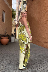 Bohemian style one shoulder maxi dress featuring a long, flowy frill that covers one arm and drapes elegantly down to the hips. This dress has side splits and showcases a large-scale bold, retro inspired print in rich green and cream tones. Made in 100% rayon.