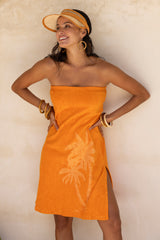 This vintage inspired strapless terry towelling dress, with its elasticated top, slips on effortlessly. Tangerine in colour and finished with our signature screen-printed palm design and a chic side split, it’s a timeless piece with a touch of sophistication. Made in a cotton / elastane blend.