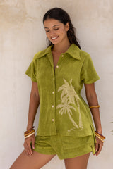 With and oversized 70s retro collar this button up terry towelling shirt with coconu buttons gives full 70s vibes. Worn with the matching shorts it's the perfect retro shirt and shorts set. Olive green with hand screen palm print. Cotton / elastane blend