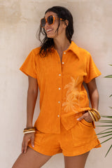 With an oversized 70s retro collar this button up terry towelling shirt with coconut buttons gives full 70s vibes. Worn with the matching shorts it's the perfect retro shirt and shorts set. Tangerine with hand screen palm print. Cotton / elastane blend