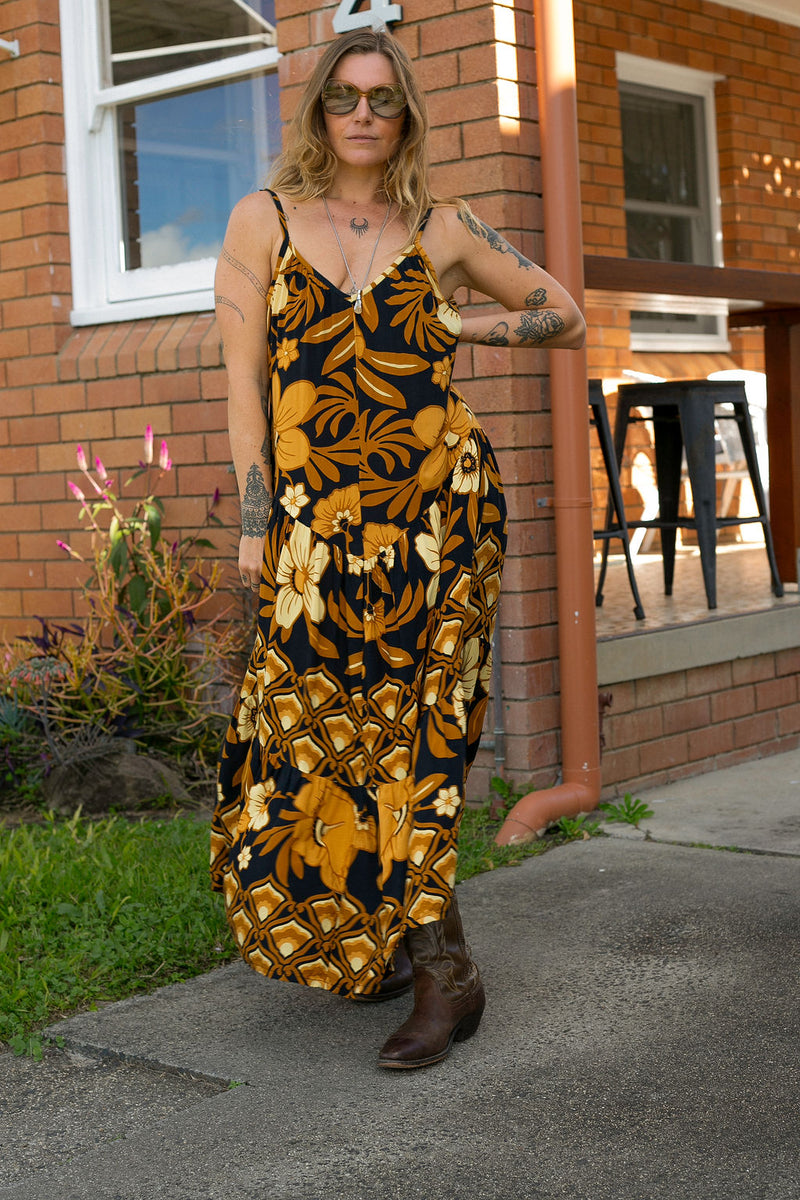 V-neck bohemian style floaty maxi dress with a low v-back and double layered frills in a large scale floral print in brown and gold tones with a black background