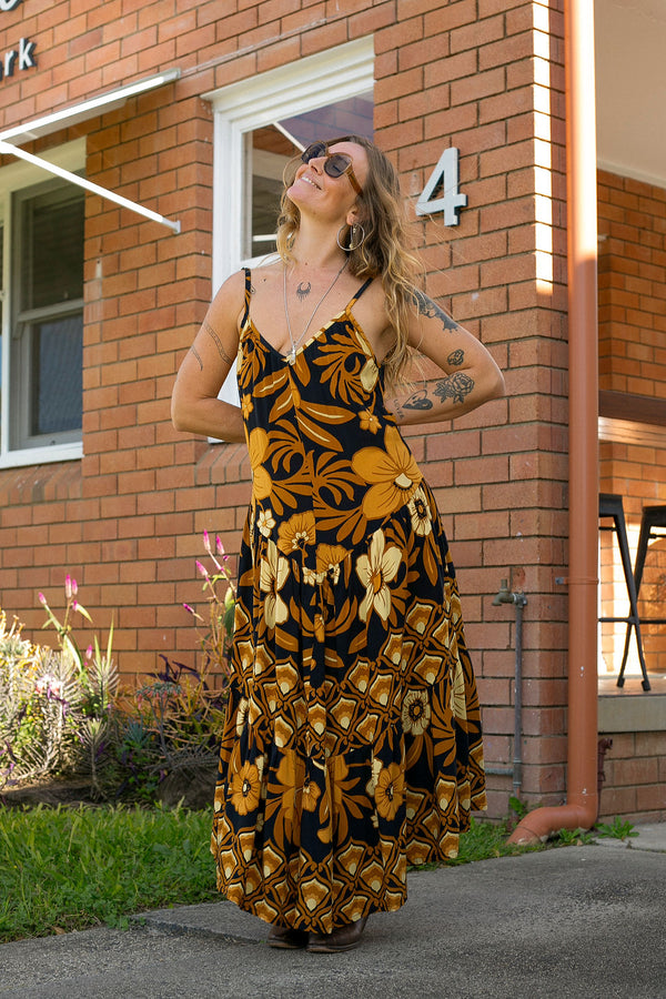 V-neck bohemian style floaty maxi dress with a low v-back and double layered frills in a large scale floral print in brown and gold tones with a black background