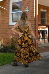 V-neck bohemian style floaty maxi dress with a low v-back and double layered frills in a large scale floral print in brown and gold tones with a black background