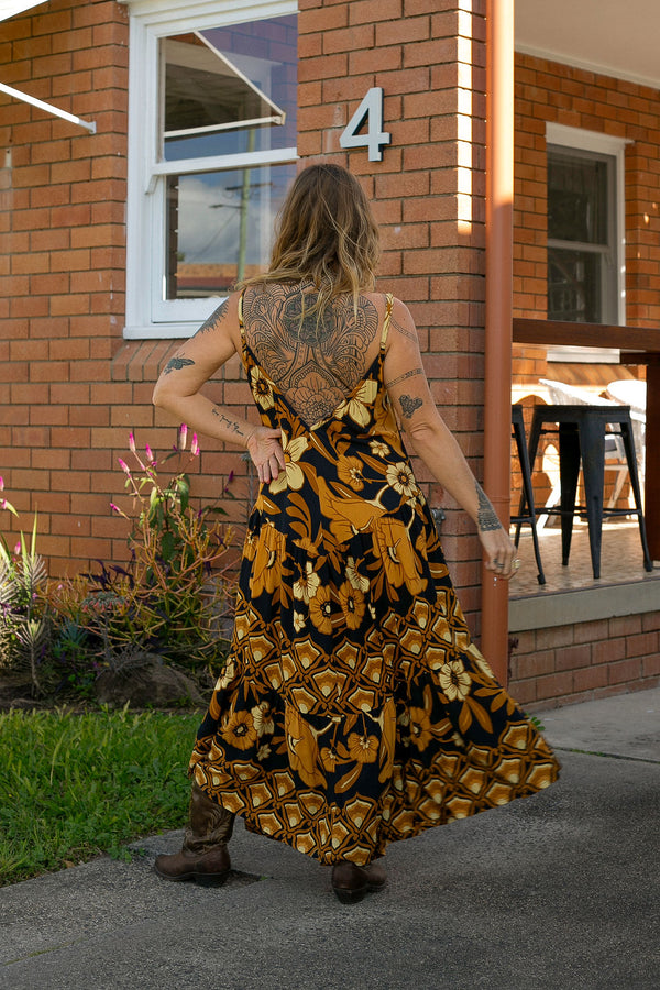 V-neck bohemian style floaty maxi dress with a low v-back and double layered frills in a large scale floral print in brown and gold tones with a black background