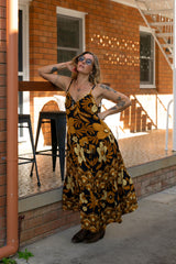 V-neck bohemian style floaty maxi dress with a low v-back and double layered frills in a large scale floral print in brown and gold tones with a black background