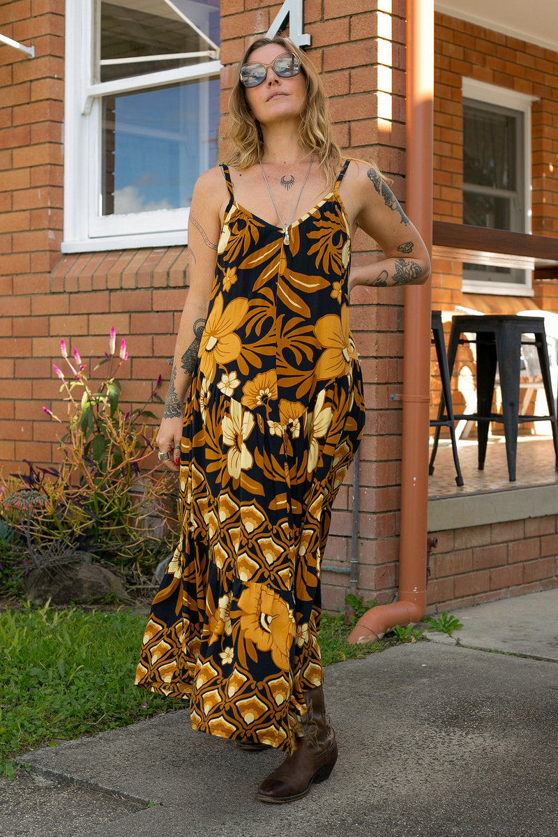 V-neck bohemian style floaty maxi dress with a low v-back and double layered frills in a large scale floral print in brown and gold tones with a black background