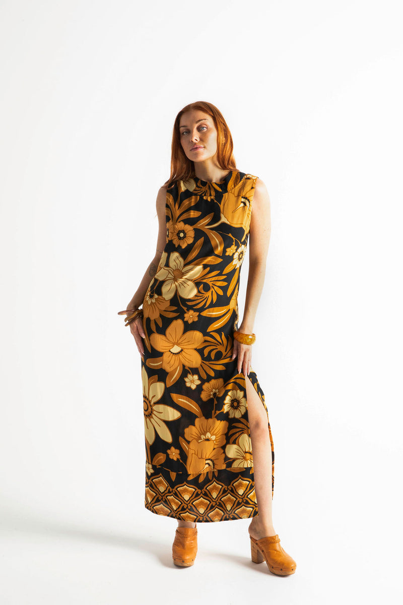 Bold floral vintage style maxi dress in a soft rayon voile with high bateau neckline and retro large scale brown and gold tone flowers on a black background
