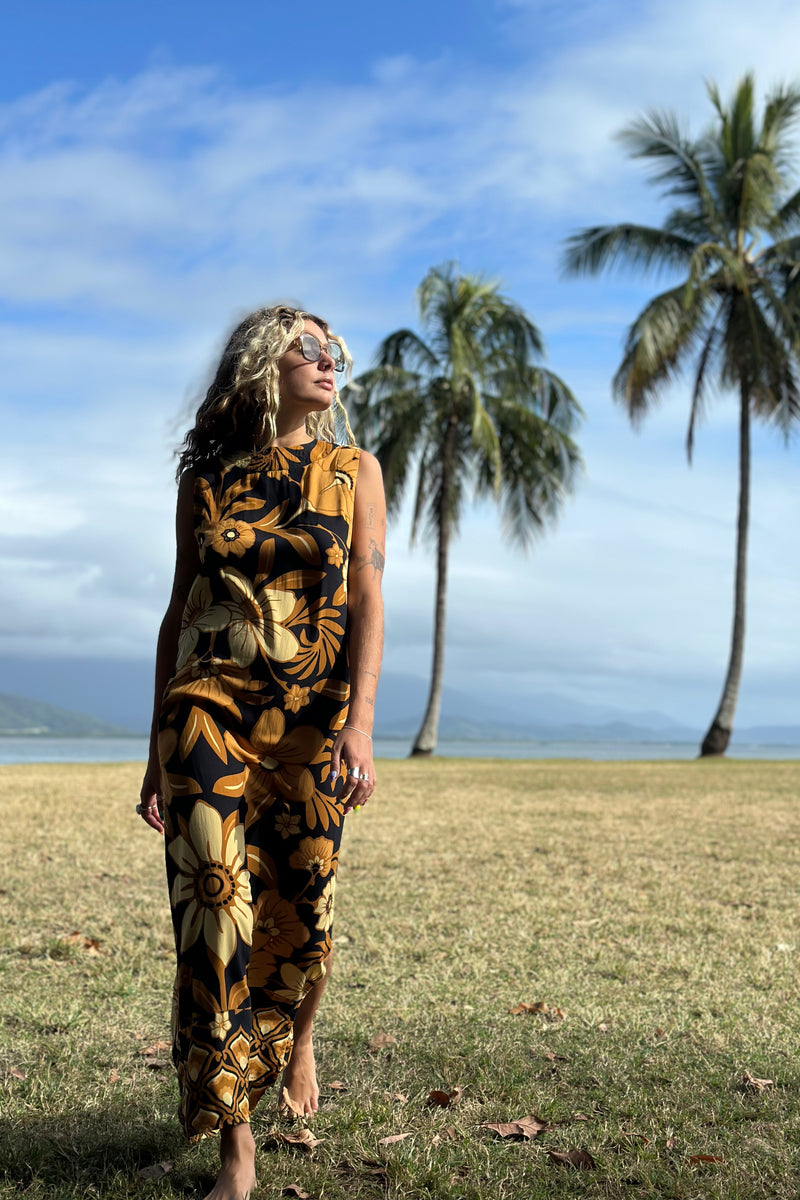 Bold floral vintage style maxi dress in a soft rayon voile with high bateau neckline and retro large scale brown and gold tone flowers on a black background
