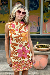 Bold floral vintage style mini dress in a soft rayon voile with high bateau neckline and retro  large scale orange and pink flowers on a buttery cream background