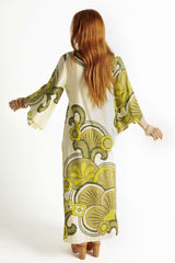 Back view of our 70s inspired maxi kaftan-style dress with bell sleeves , retro patch pockets and a v-neckline. Features a bold, large-scale  retro geo print. in rich green tones. Made in 100% cotton
