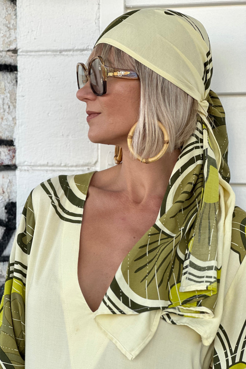 Versatile wrap that an be styled as a head wrap, scarf, wrap around top or belt to add that vintage-chic flair to any outfit. Made in 100% rayon in a green and cream, bold large scale retro print