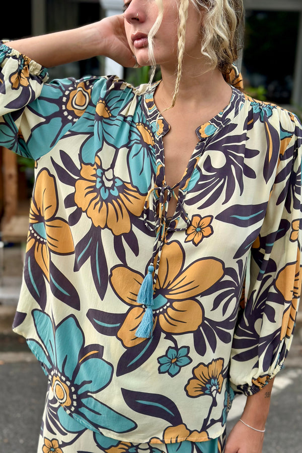 Vintage inspired bohemian style blouse with a v neckline and tie details in a large scale floral print in blues and mustard with a cream  background