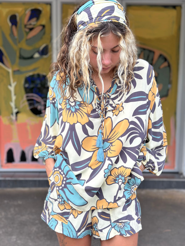 Vintage inspired bohemian style blouse with a v neckline and tie details in a large scale floral print in blues and mustard with a cream  background