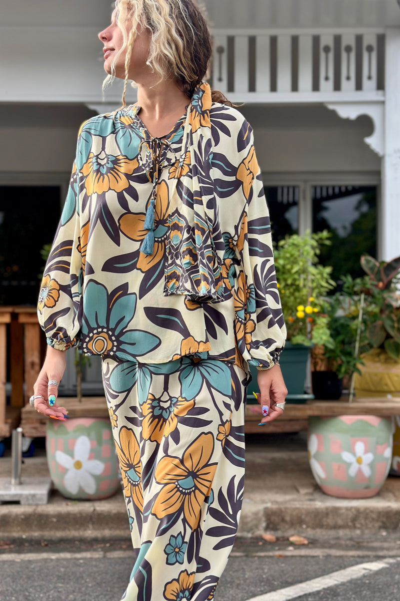 Vintage inspired bohemian style blouse with a v neckline and tie details in a large scale floral print in blues and mustard with a cream  background