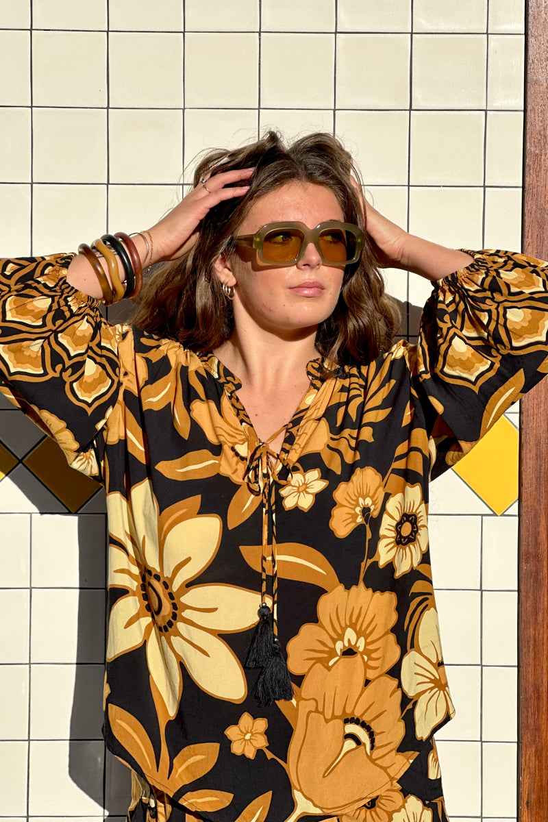 Vintage inspired bohemian blouse with a v- neckline and tie details in a large scale floral print in brown and gold tones with a black background