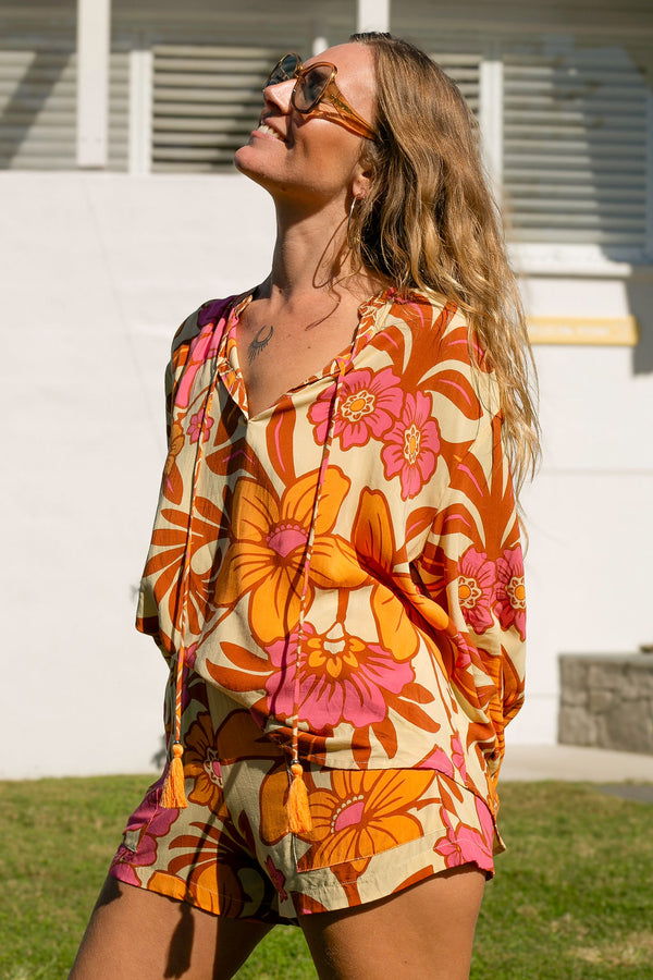 Vintage inspired bohemian style blouse with a v neckline and detail ties in a large scale retro floral print pink and orange flowers on a buttery cream background