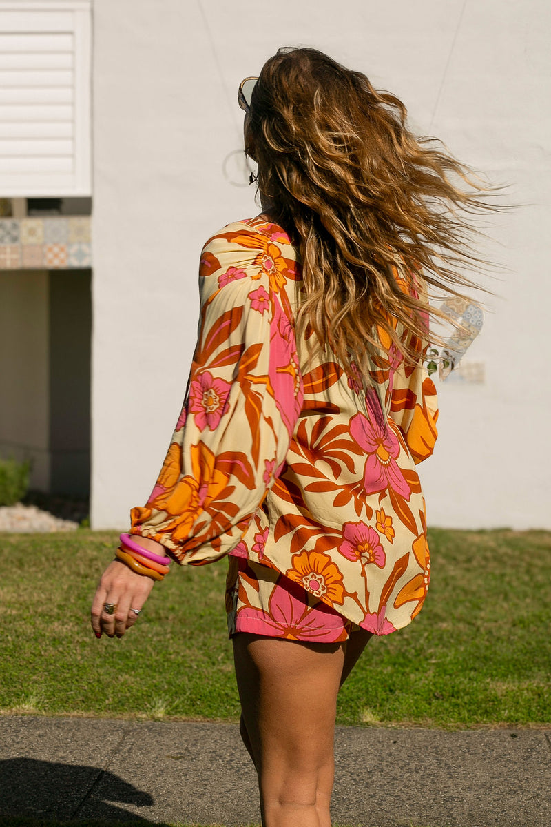 Vintage inspired bohemian style blouse with a v neckline and detail ties in a large scale retro floral print pink and orange flowers on a buttery cream background