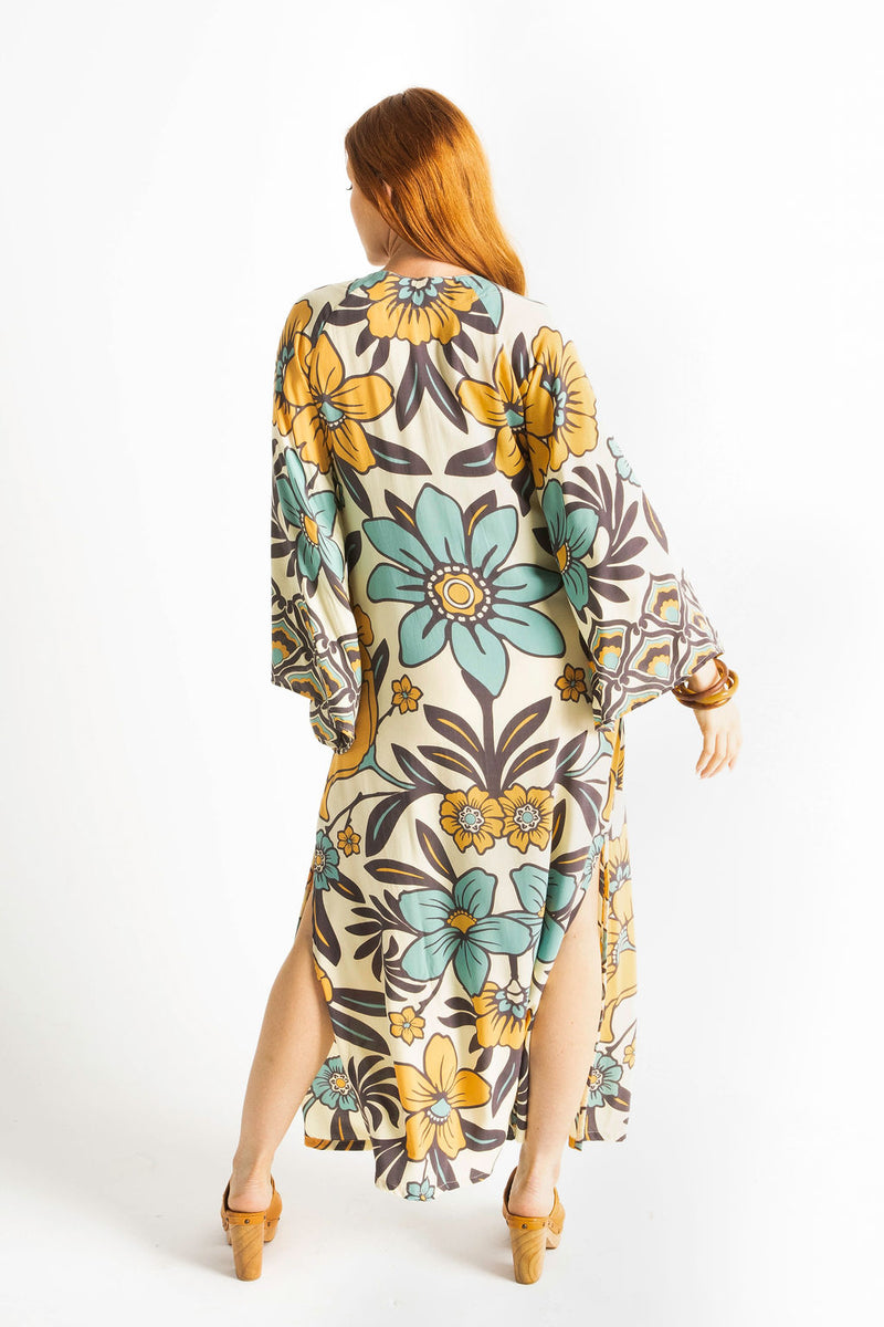 70s vintage inspired boho midi dress with bold retro floral print in blue,tan and navy on a cream background, bell sleeves and side splits. Made in rayon