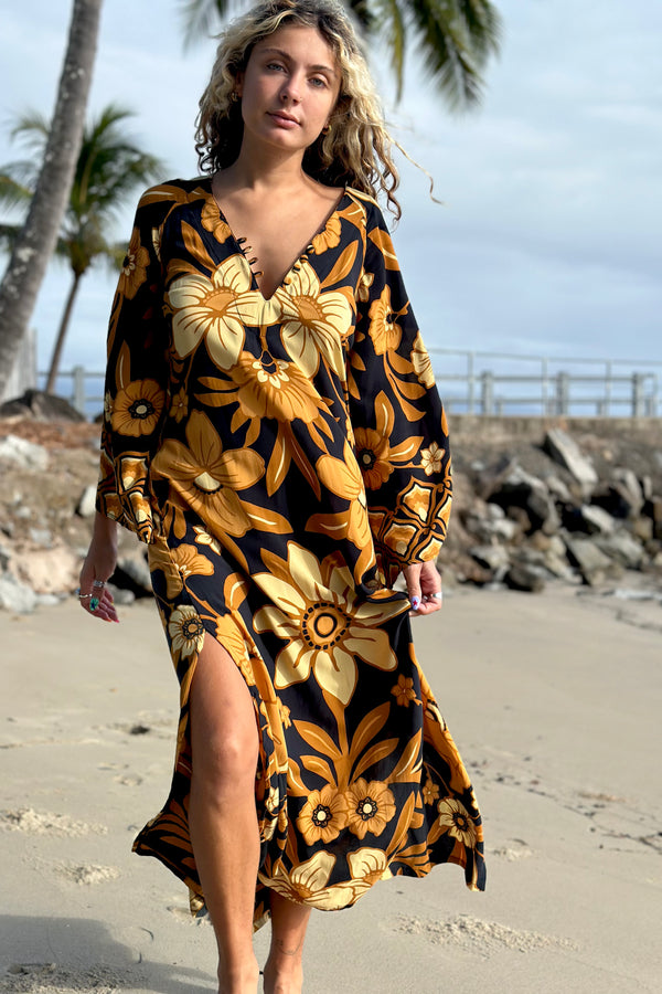70s vintage inspired boho midi dress with bold retro floral print in brown,gold and cream tones on a black background, bell sleeves and side splits. Made in rayon