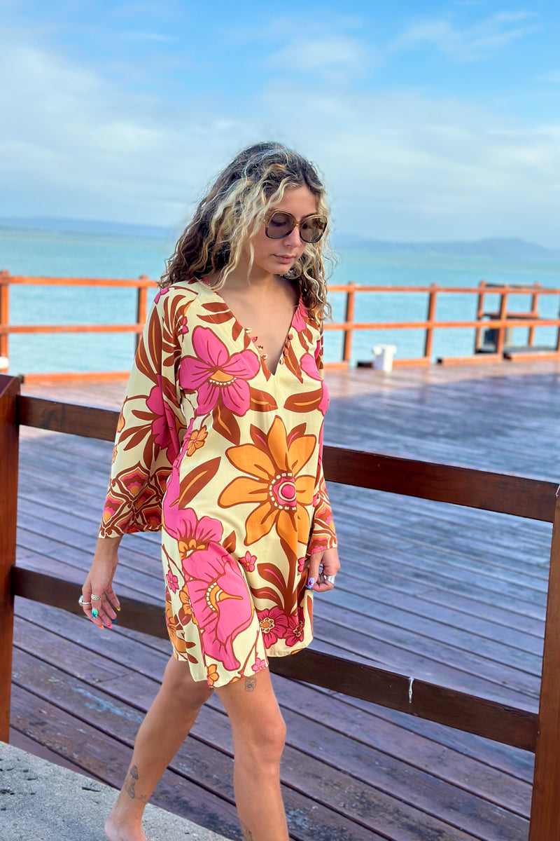 70s vintage inspired boho mini dress with bold retro floral print in Pink and orange tones on a buttery cream background, bell sleeves and side splits. Made in rayon