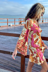 70s vintage inspired boho mini dress with bold retro floral print in Pink and orange tones on a buttery cream background, bell sleeves and side splits. Made in rayon