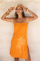 This vintage inspired strapless terry towelling dress, with its elasticated top, slips on effortlessly. Tangerine in colour and finished with our signature screen-printed palm design and a chic side split, it’s a timeless piece with a touch of sophistication. Made in a cotton / elastane blend.
